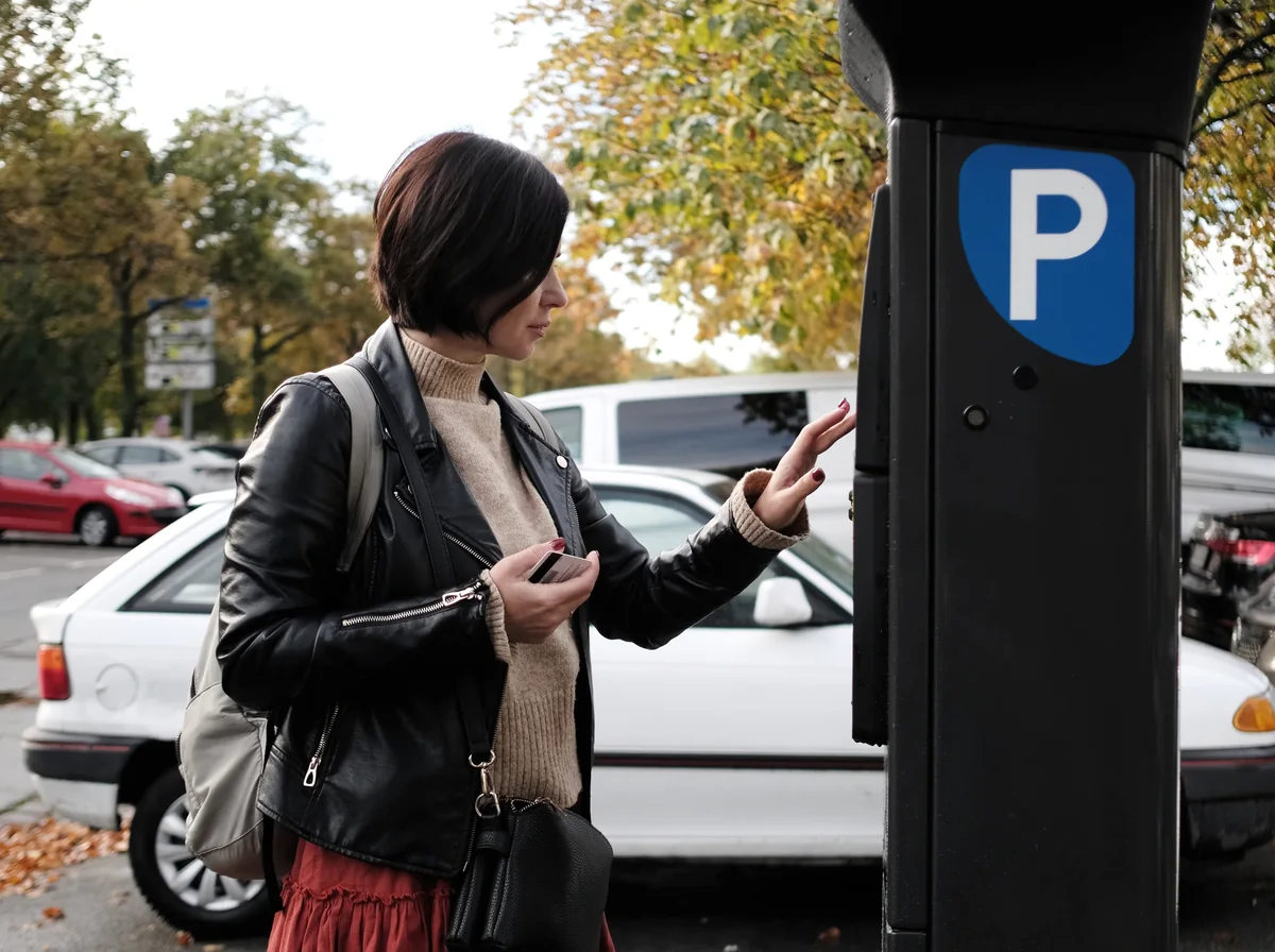 Frau am Parkscheinautomat auf einem bewirtschafteten Parkplatz